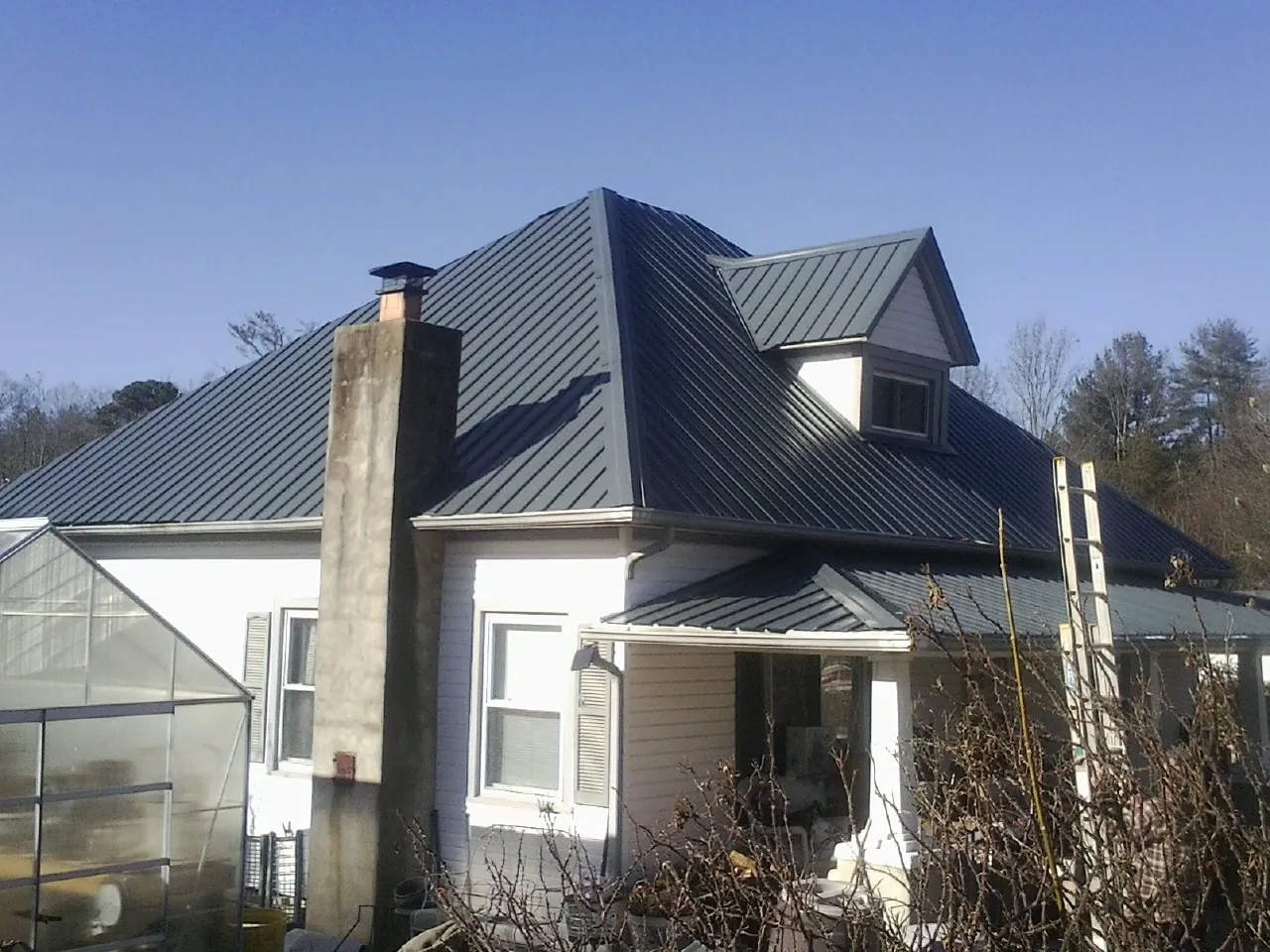 Dark blue standing seam metal roof on a white farmhouse with dormer — Slate & Tile Roof Repair by Roofing Brothers in Ellerslie