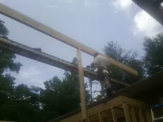Carpenter setting a ridge beam over a new addition frame — Ice Dam Removal by Roofing Brothers in Ellerslie
