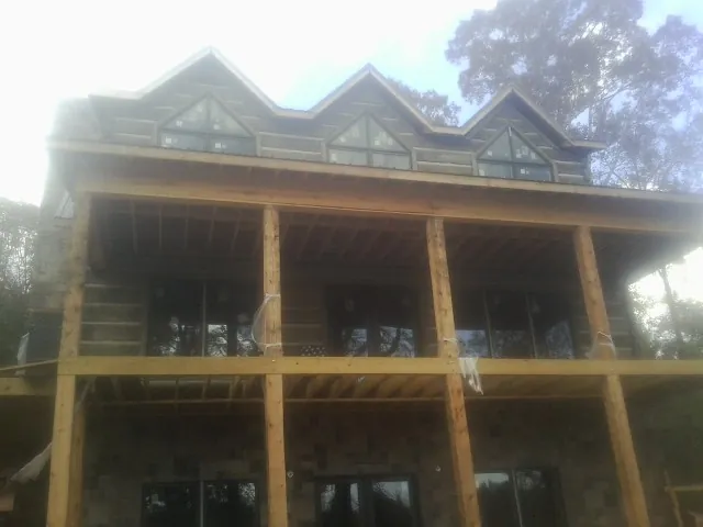 Dormers and porch framing on a large log home under construction — Roof Coating work by our crew in Ellerslie