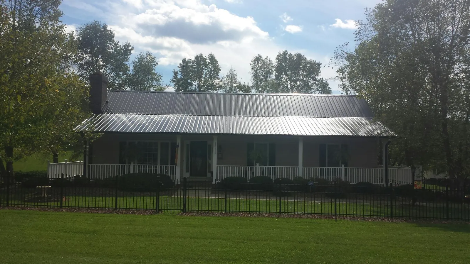 Gray metal roof on a brick ranch with a full width front porch — Gutter Guard Installation work by our crew in Ellerslie