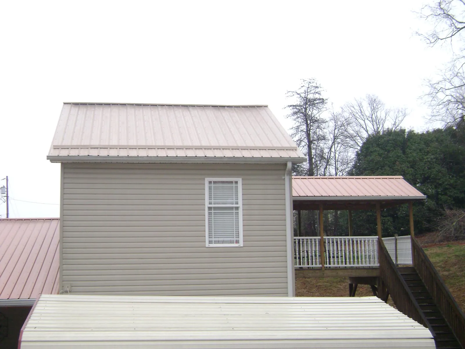 Tan metal roofs on a two story addition and attached porch, from a Roof Replacement job in Ellerslie