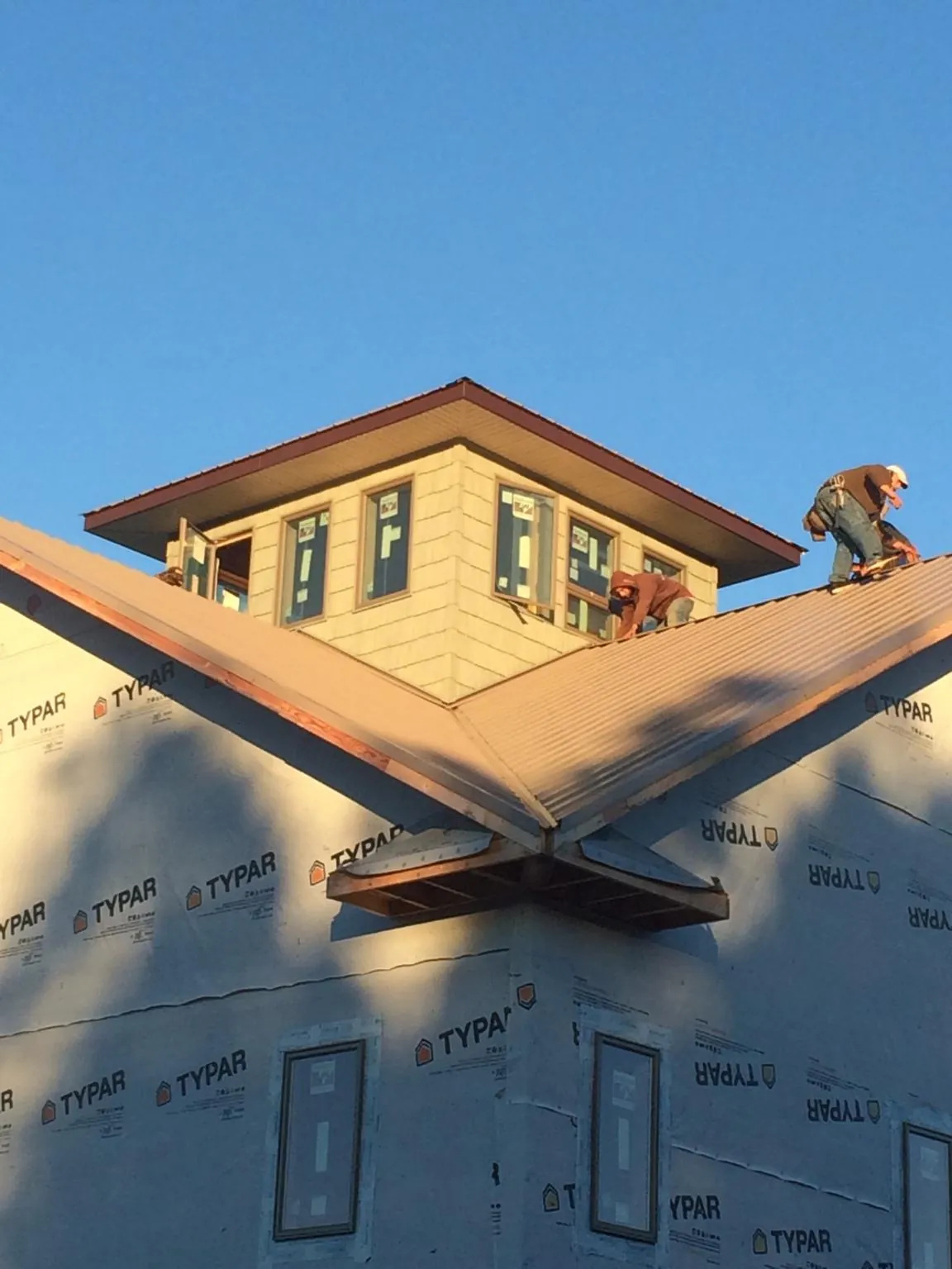 Roofers working around a rooftop cupola on a new metal roof at sunset — Roof Waterproofing in Ellerslie by Roofing Brothers